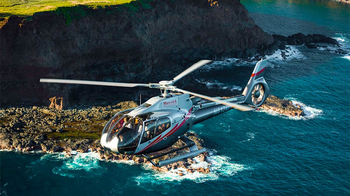 A helicopter flies above the vast blue ocean.